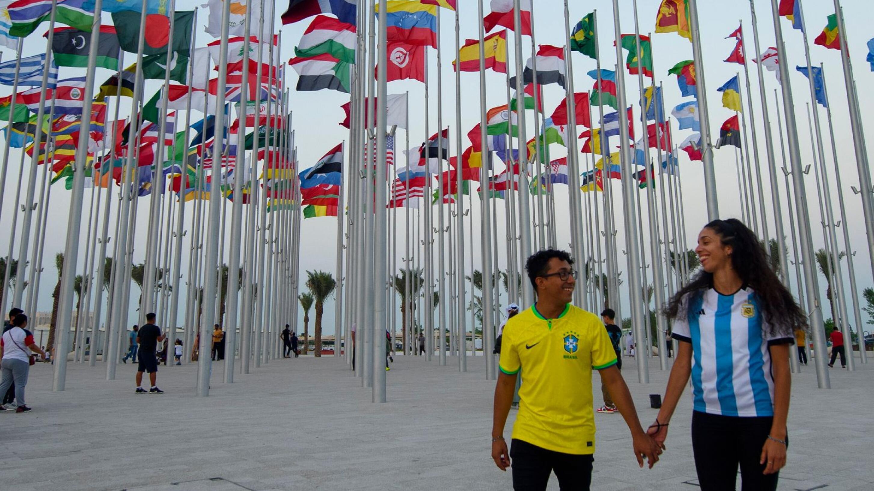 two soccer fans walk in a a Flag Plaza in Doha, Qatar