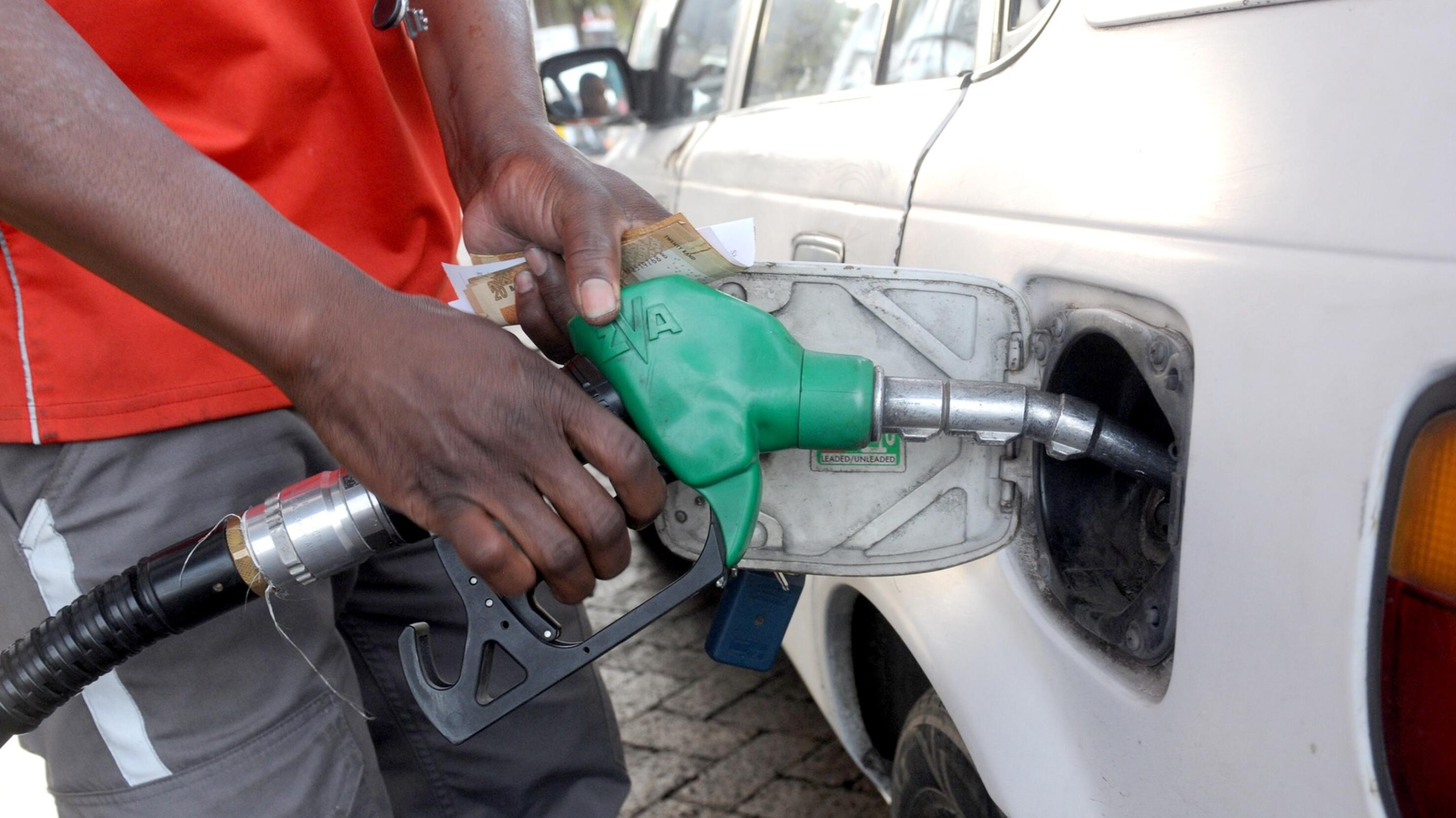 A petrol attendant fills fuel into the tank of a vehicle.