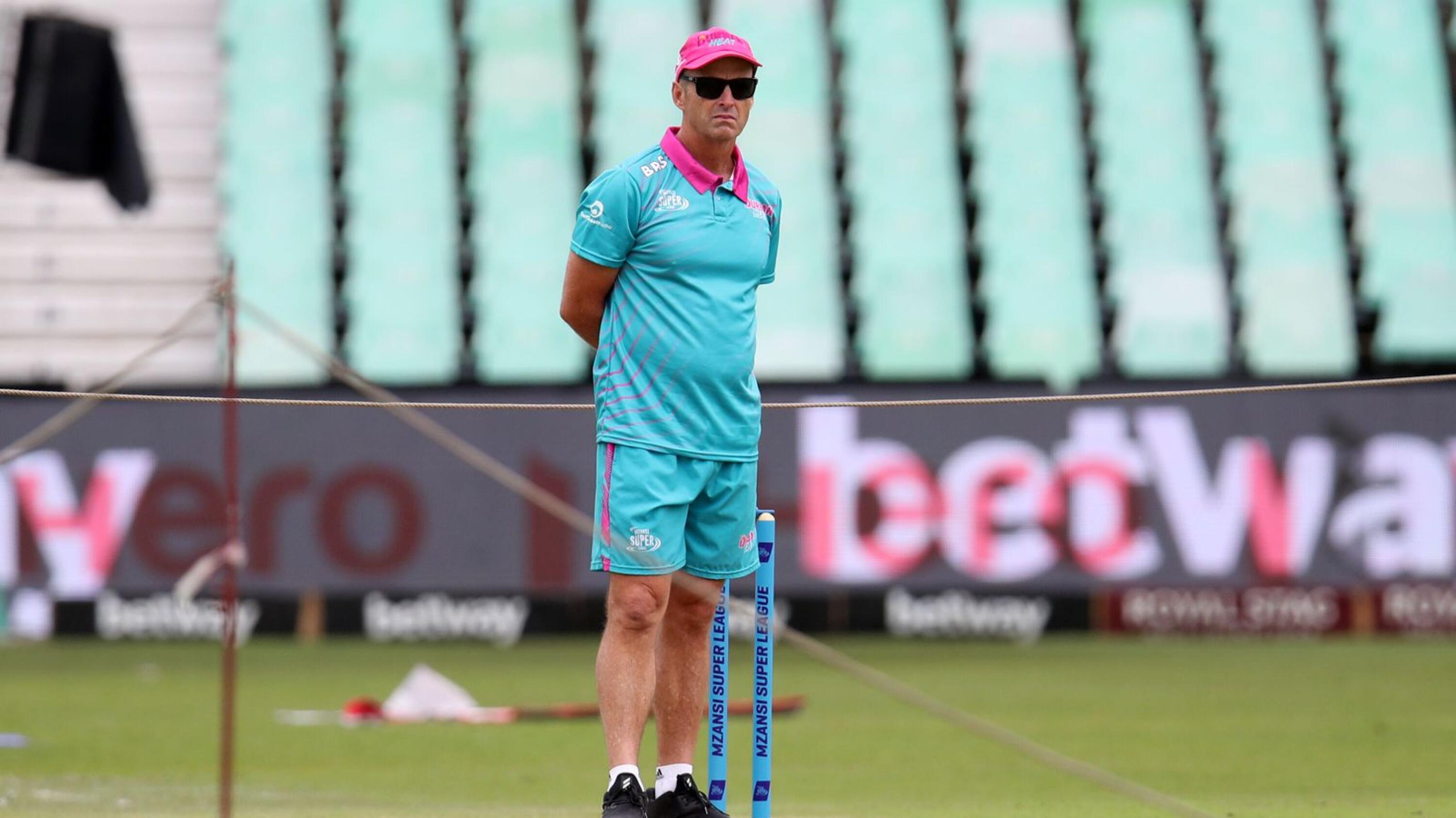 a cricket coach watches on during a training session