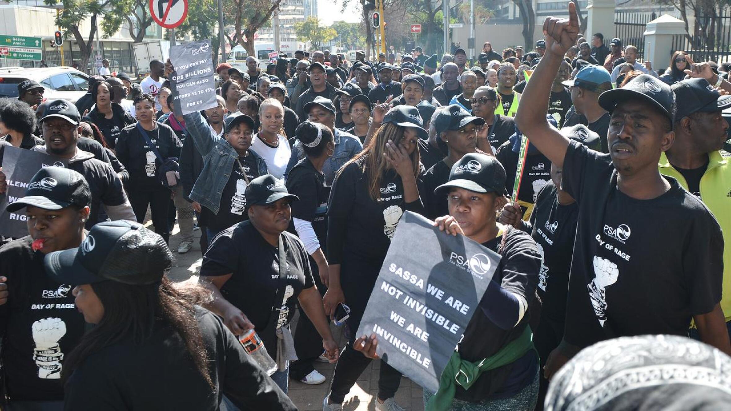 Union members dressed in black hold up posters during a protest.