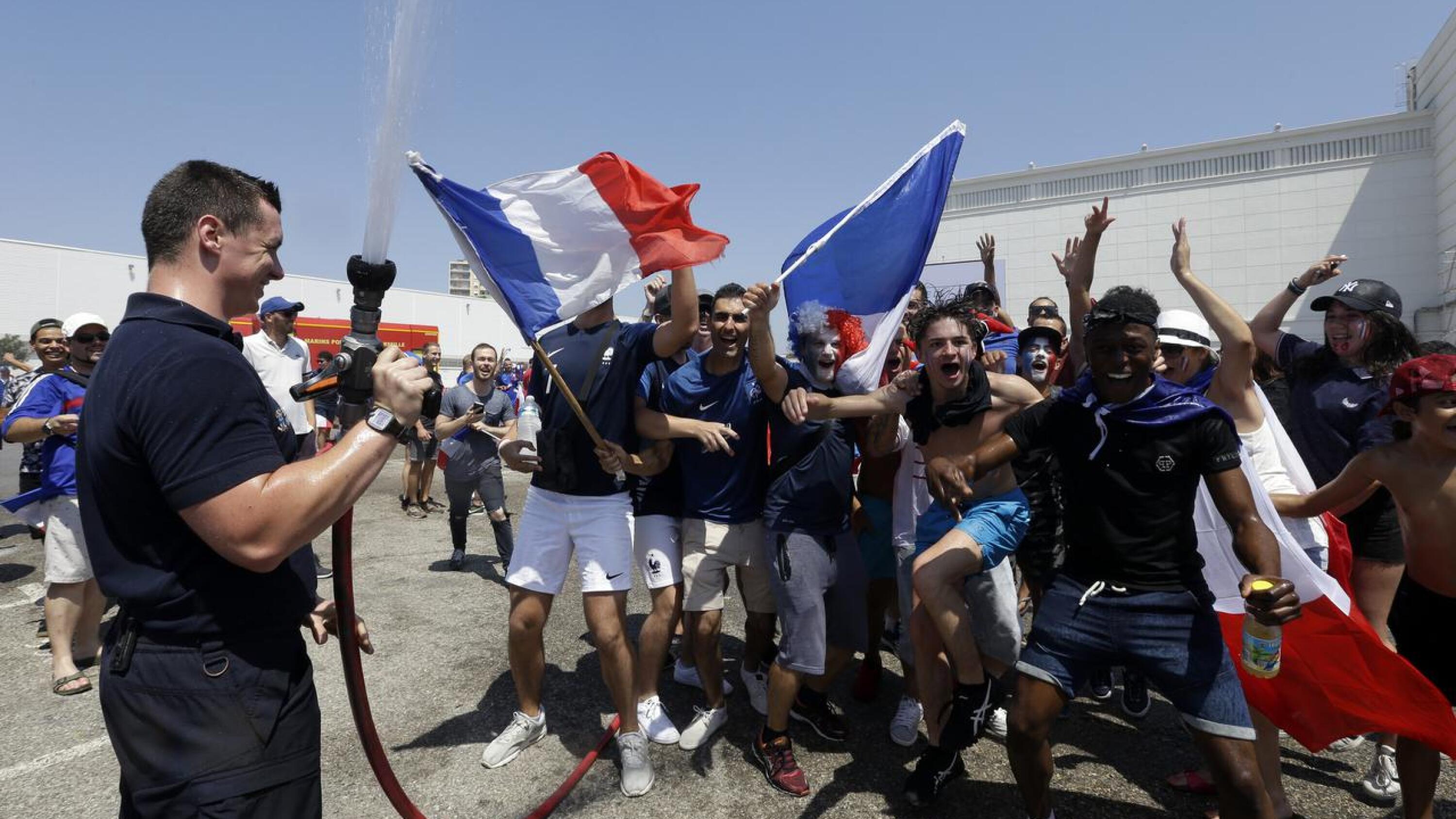 A firefighter sprays water to cool off French supporters at a fan zone in Marseille prior to the World Cup final between France and Croatia