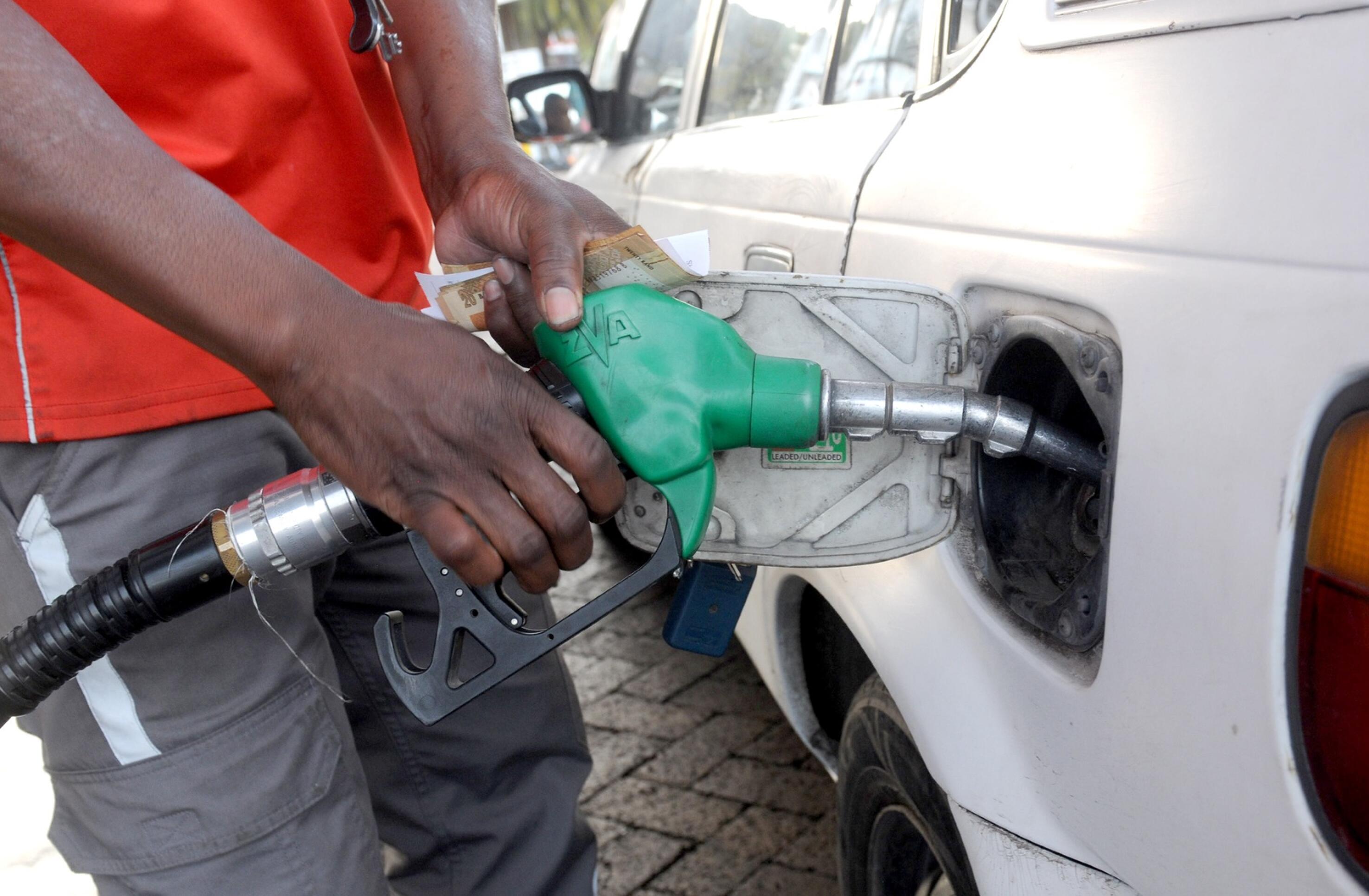 An attendant at a fuel station fills fuel in a vehicle.