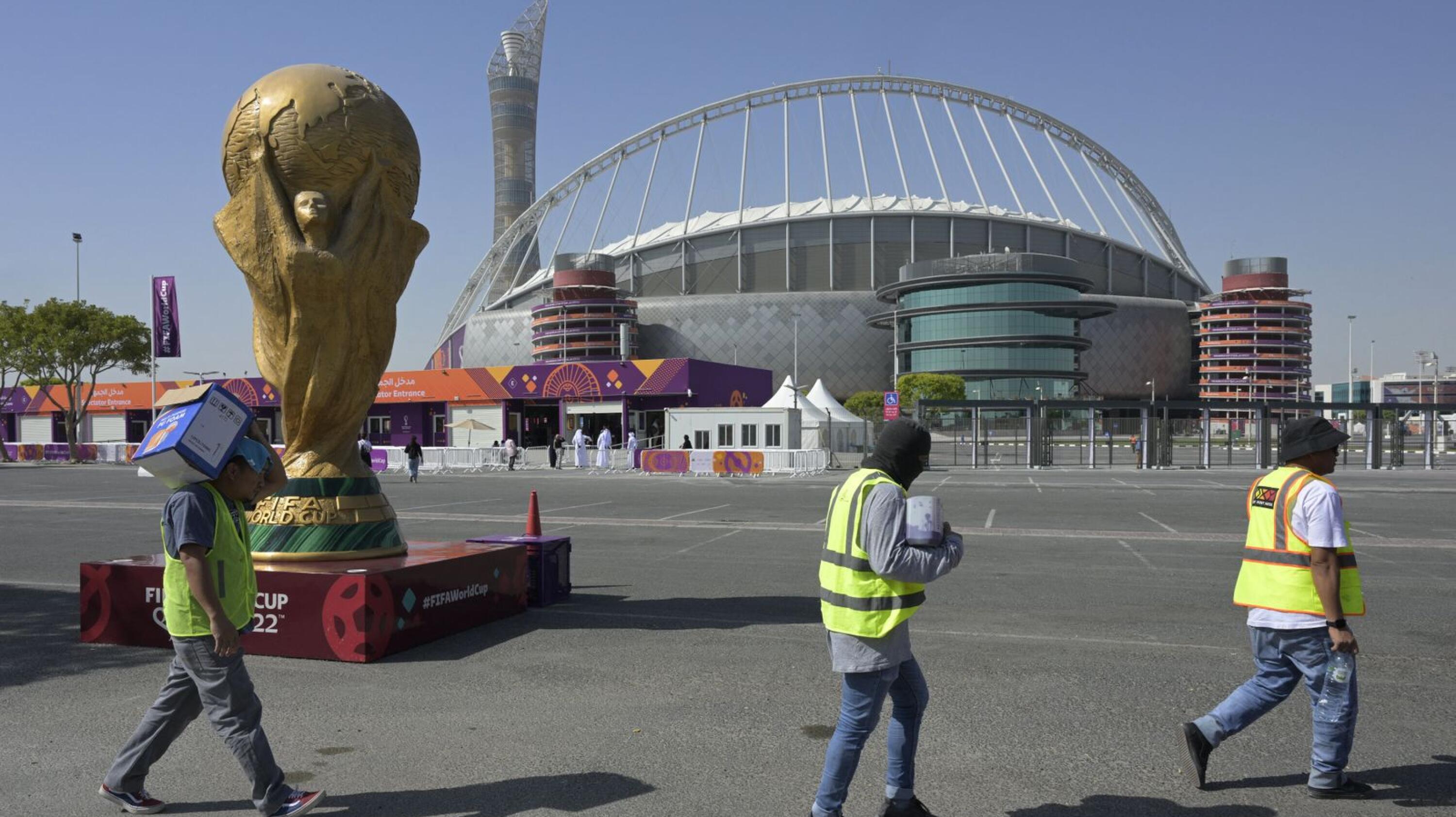 Workers walk past the Khalifa International Stadium in Doha ahead of the Qatar 2022 World Cup football tournament