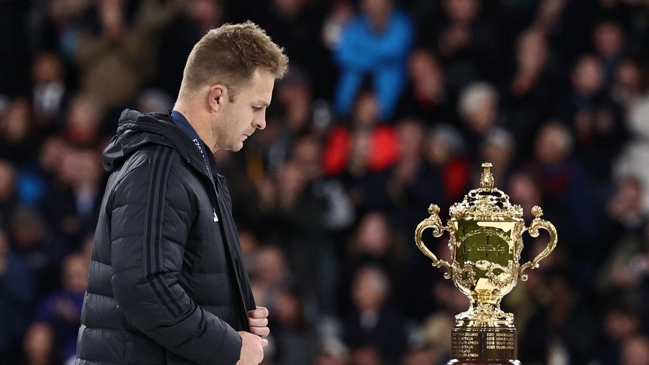 New Zealand's openside flanker and captain Sam Cane reacts as he walks past the Web Ellis Cup after South Africa won the France 2023 Rugby World Cup Final match between New Zealand and South Africa at the Stade de France in Saint-Denis, on the outskirts of Paris