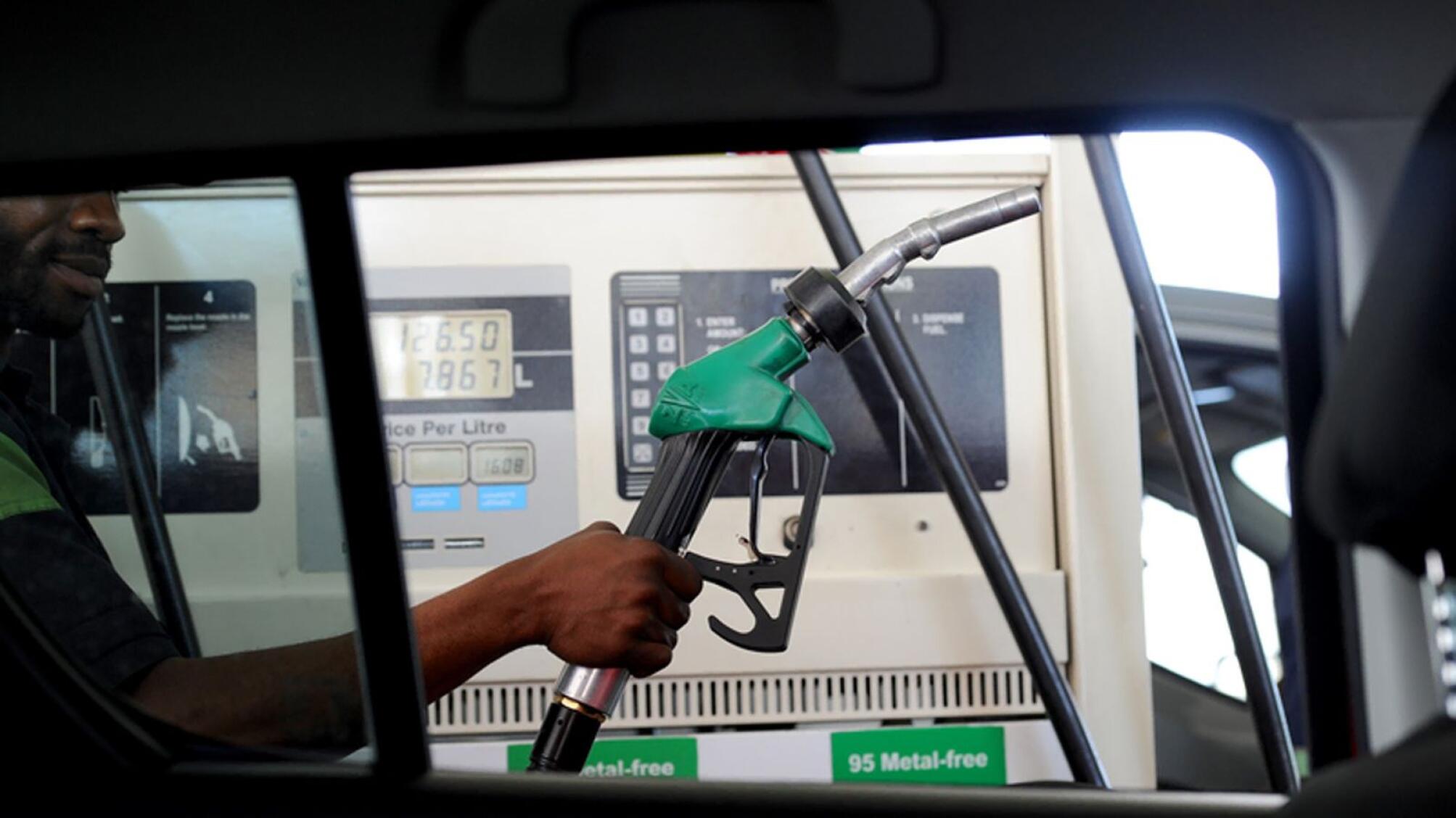 A fuel station attendant fills fuel in a car. 