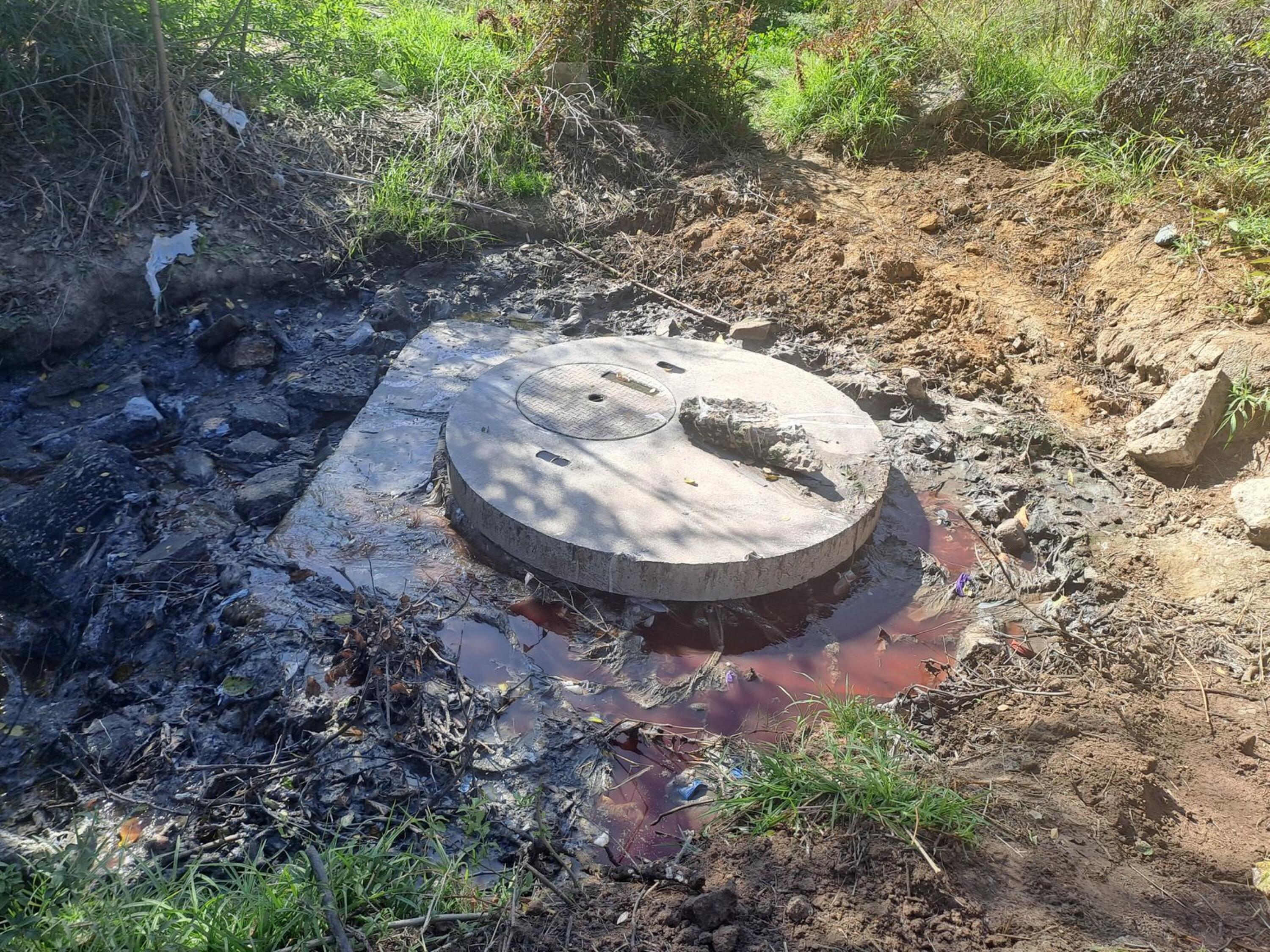 An image of sewage flowing from a manhole near the Vaal River.