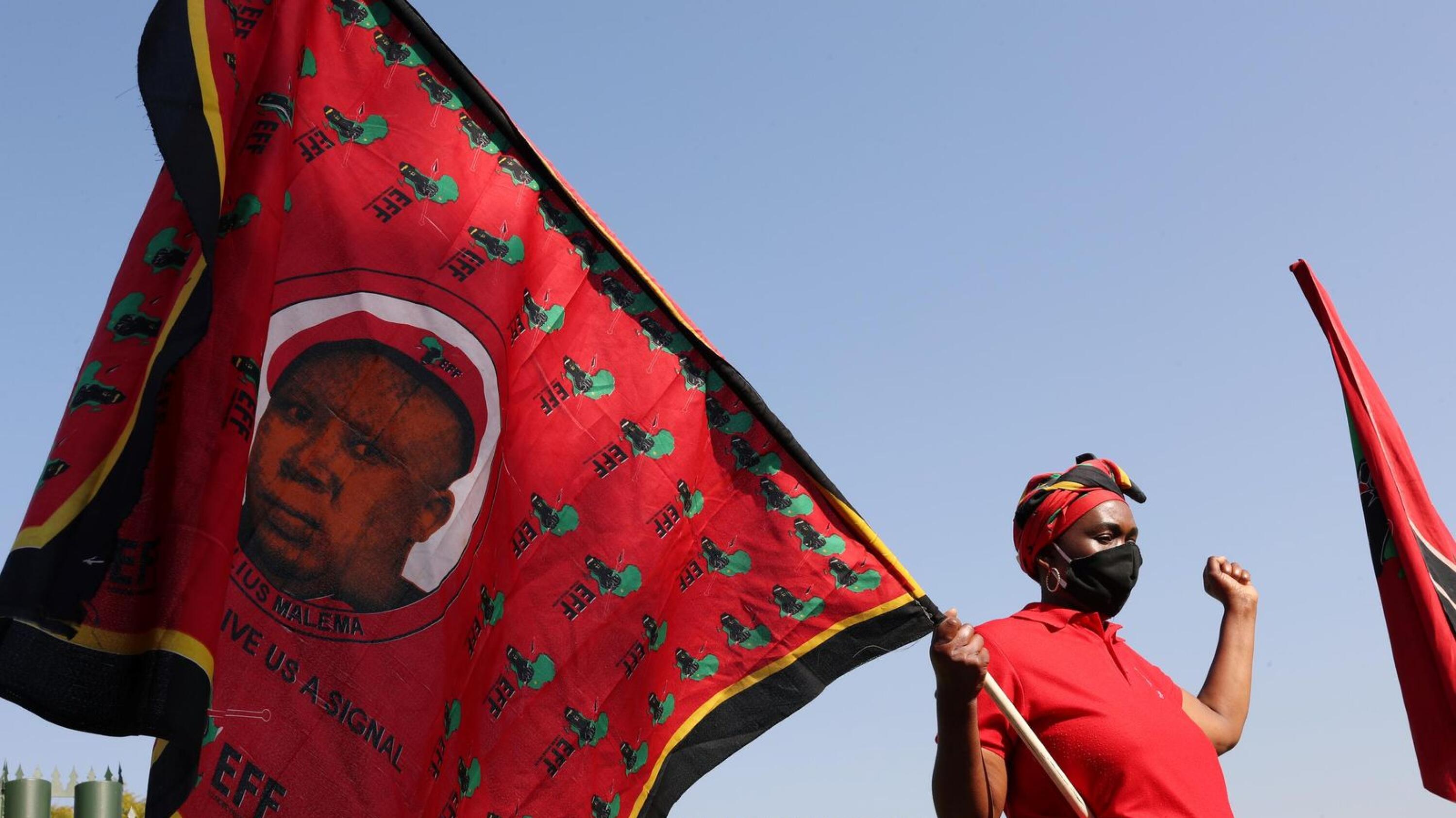 A member of South Africa's opposition party the Economic Freedom Fighters (EFF) holds a flag with an image of the party leader Julius Malema 