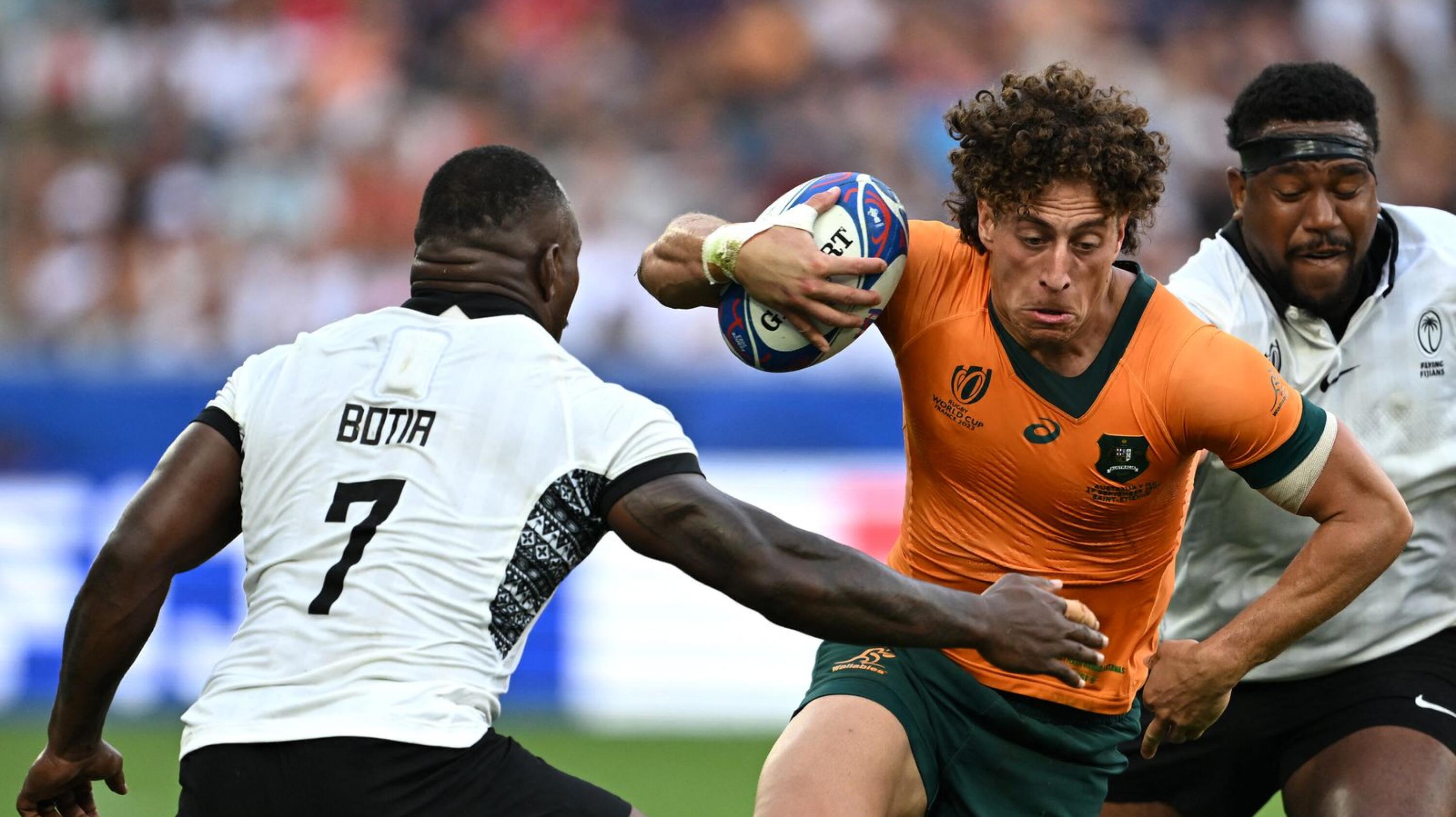Australia's right wing Mark Nawaqanitawase runs with the ball as he tries to evade a tackle by Fiji's Levani Botia during their Rugby World Cup Pool C match