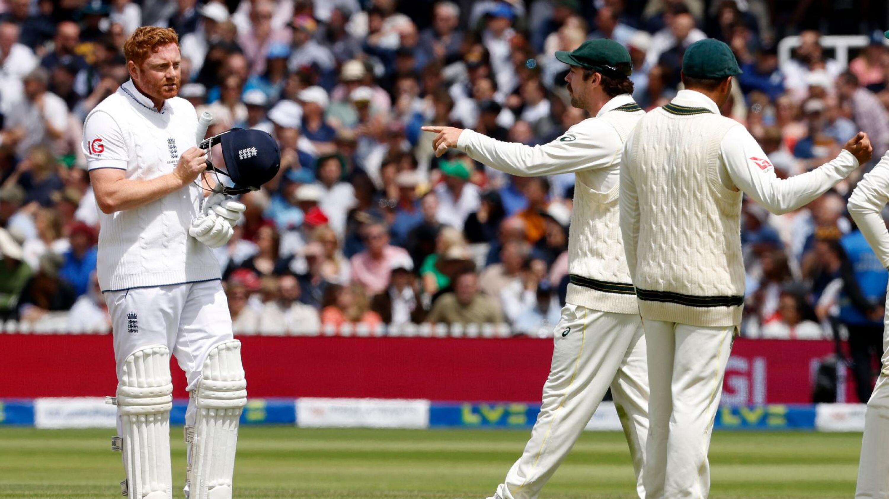Australia's Travis Head (C) points as he talks with England's Jonny Bairstow whilst the await the successfully appeal for Bairstow's wicket for 10 runs on day five of the second Ashes cricket Test match between England and Australia at Lord's cricket ground