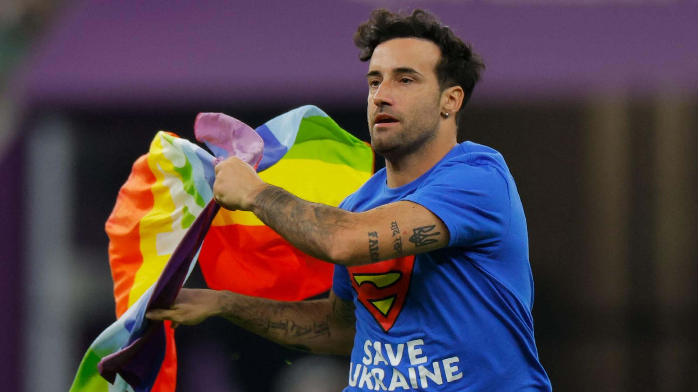 A man wearing a t-shirt reading ‘Save Ukraine’ runs on the pitch waving a rainbow flag on the pitch during the Qatar 2022 World Cup Group H football match between Portugal and Uruguay at the Lusail Stadium in Lusail on Monday