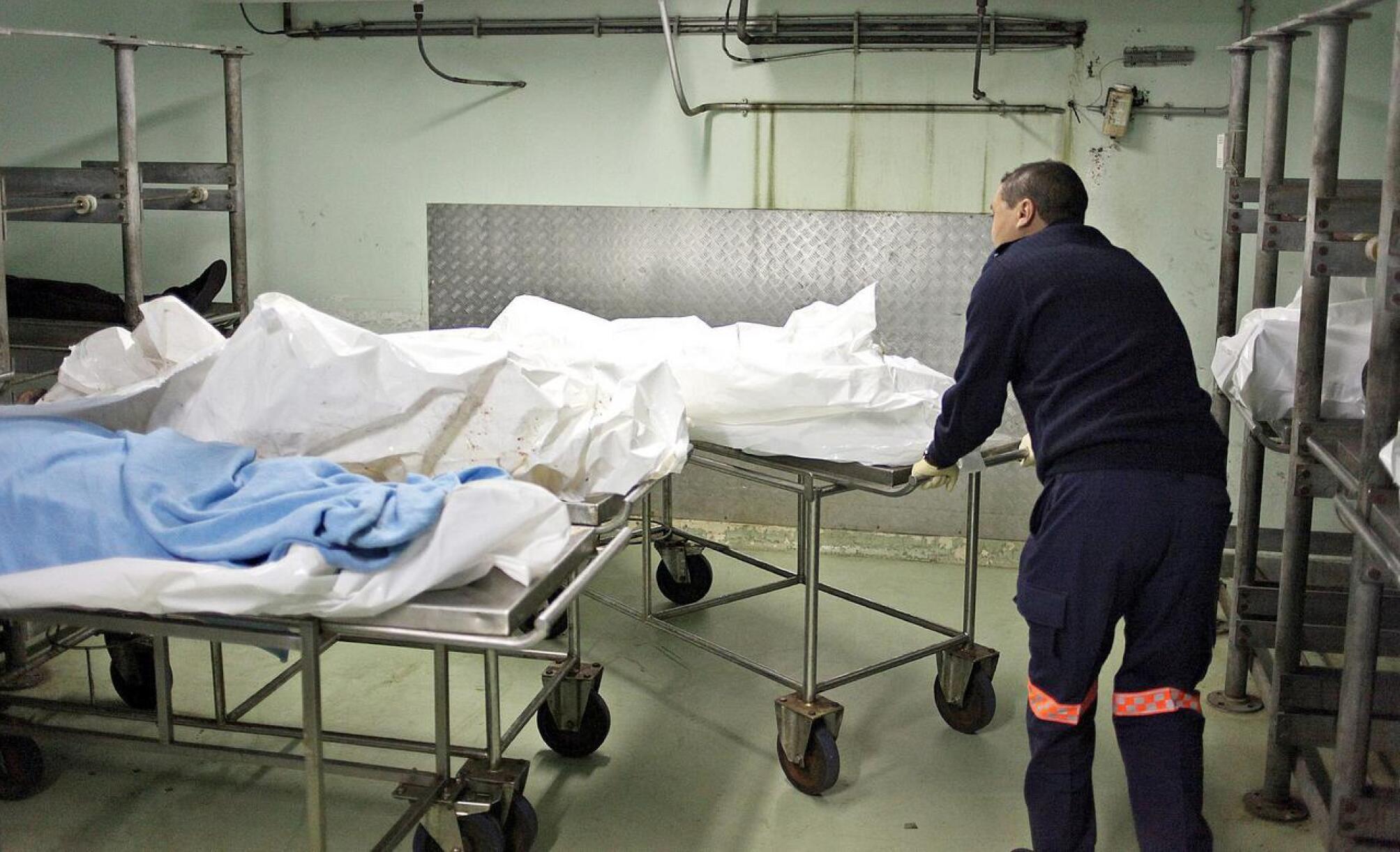 A forensic pathology employee pushing bodies 