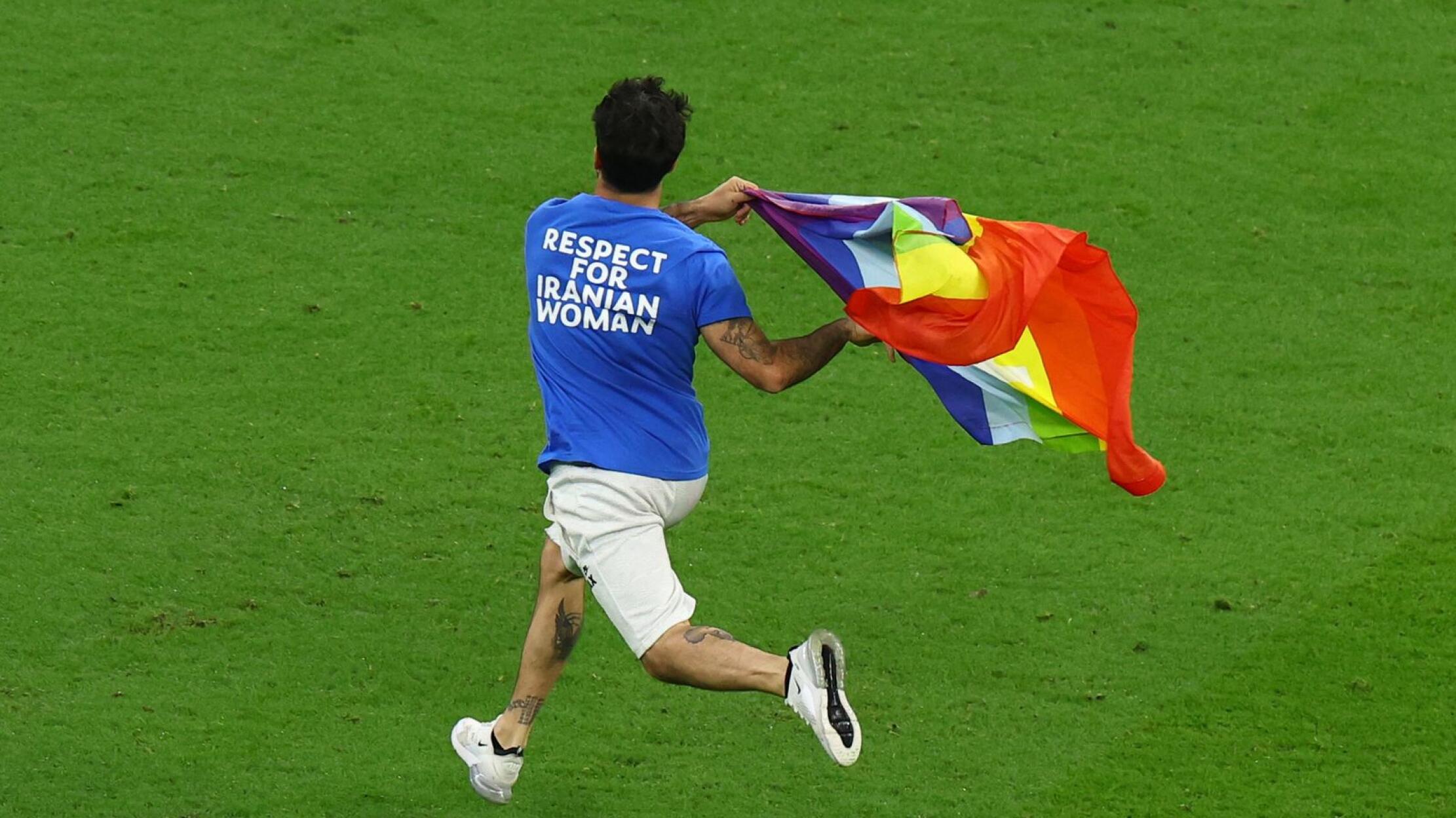 A pitch invader runs onto the pitch wearing a t-shirt with a message saying 'Respect for Iranian Women' and holding a rainbow flag during the match between Portugal and Uruguay on Monday